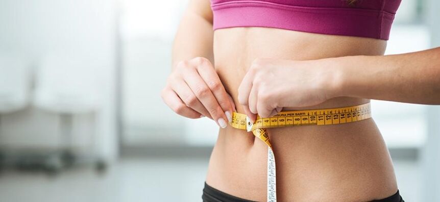 The girl measures her waist size